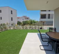 The garden of a 4-room apartment in Vodice with a terrace and a modern table on the grass.