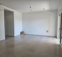 Spacious living room in a 4-room apartment with ceramic flooring and white walls.