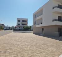 In Vodice, modern apartment buildings and a paved access road are visible.