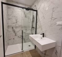 Shower corner with a sink in the bathroom of a 4-room apartment, with marble walls.