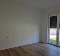 An empty room in a three-room apartment with a wooden floor and a large window.