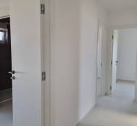 Hallway of a 4-room apartment with white walls and open doors.