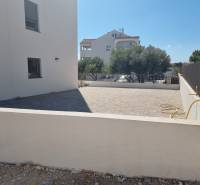 A yard with a 4-room apartment in Vodice with a paved terrace and a low fence.