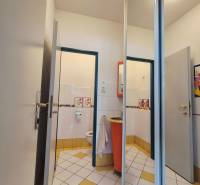 A restroom with white and yellow tiles and an orange sink in a commercial space.