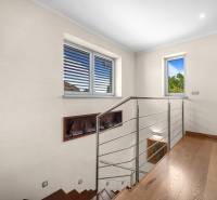 Wooden staircase with metal railing, bookshelf, and windows in a family house.
