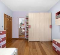 Children's room in a family house with pink and purple dressers, a mirror, and wooden flooring.