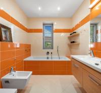 A bathroom in a family house with orange-beige tiles, a bathtub, a sink, and a bidet.
