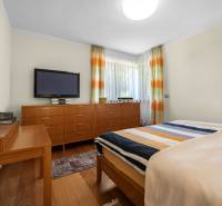 A bedroom in a family house with wooden furniture, a TV, and colorful curtains.