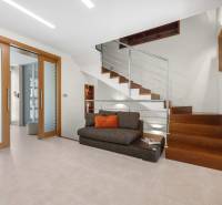 A family house with wooden stairs, glass, and a sofa with a cushion.