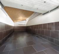 A garage with ceramic tiles in a family house, walls covered with brown cladding.