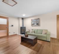 Living room with wooden flooring, green sofa, and tiled fireplace in a family house.