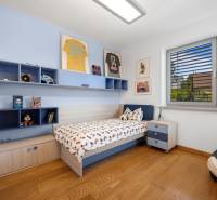 A children's room in a family house with a bed, shelves, pictures, and modern furnishings.