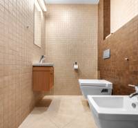 A bathroom in a family house with beige tiles, a bidet, and a wall-mounted toilet.