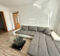 A bright living room with a corner sofa and a glass table in a two-room apartment.