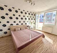 Bedroom in a two-room apartment with patterned wallpaper and a double bed.
