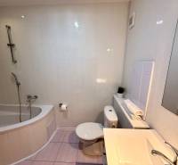 Bathroom in a 2-room apartment with a bathtub, sink, and toilet, light tiles.