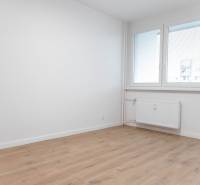 A room with a wooden floor, walls, and large windows in a 2-room apartment.