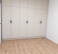 White built-in wardrobe with six doors in a 2-room apartment on a wooden floor.