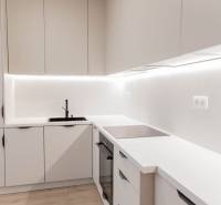 A kitchen in a 2-room apartment with white cabinets and a black sink.