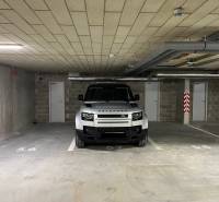 A car parking in a garage with doors and numbering on the floor.