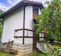 A cottage in Mojša surrounded by a green garden and fruit trees.