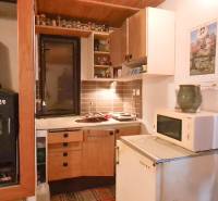 A cottage with a kitchen, stove, microwave, heating, curtains, cabinets, and wall decorations.