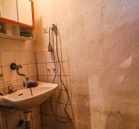 A bathroom in a cabin with a sink, a wooden ceiling, and a small window.