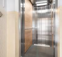 Opening a modern elevator on the floor of a residential building with a wooden decor.