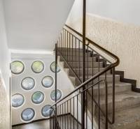 Staircase with railing, round windows, textured walls, spatial arrangement.