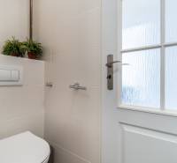 Bathroom of a 2-room apartment with a toilet, ceramic tiles, and glass doors.