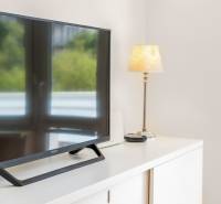 A television and a lamp on a white dresser in a 2-room apartment.