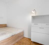 Bedroom with a bed and a dresser in a 2-room apartment, floor with wooden decor.