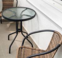 A balcony with rattan chairs and a glass table in a 2-room apartment.