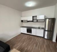 A kitchen in a 2-room apartment with a wooden floor and modern appliances.