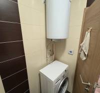 A washing machine with a water tank in the bathroom of a 2-room apartment.