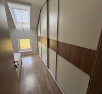 A narrow hallway with built-in wardrobes in a 2-room apartment with wooden flooring.