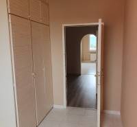 Interior of a 3-room apartment with tiles, a coat rack wall, and a passage to another room.