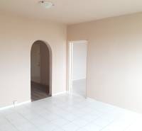 Interior of a 3-room apartment with white tiles and an arched entrance to another room.