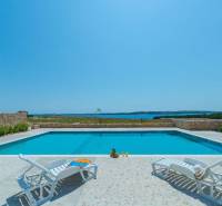 A pool at a recreational apartment in Povljane with a sea view surrounded by loungers.