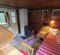 A cozy atmosphere in a cabin with a wood stove, a lamp, and a sofa with cushions.