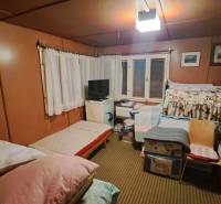 A room in a cottage with beds, a television, paintings on the walls, and a carpeted floor.
