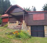 A wooden cottage in Nižné Matejkovo in Ružomberok surrounded by a forest with a flower bed.