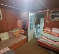 A cozy room in the cottage with a sofa, duvets, and pictures on the walls.