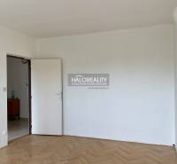 Empty room with a white wall and wooden floor in a 3-room apartment.
