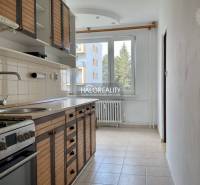A kitchen in a 3-room apartment with a wooden cabinet, stove, and a window with a radiator.