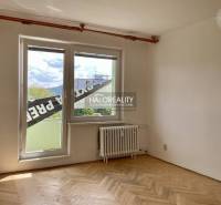 A room with parquet floors and a large window in a three-room apartment.