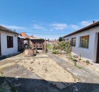 The courtyard of a family house in Písniky in Malacky with a crumbling concrete surface and structures.