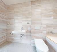 Bathroom in a family house with beige tiles, a sink, and a toilet.