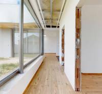 A simple hallway with wooden flooring and large windows in a family house.