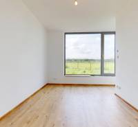 A bright room with wooden flooring and a large window in a family house.